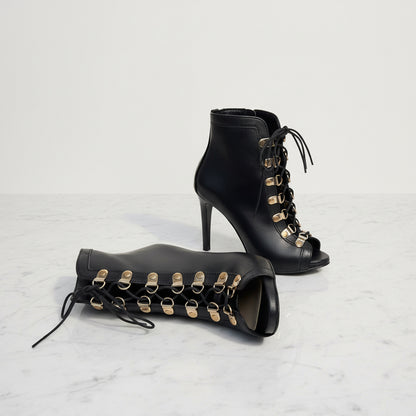 ORIA boots pair on marble, gold lace hoop detail with sleek black leather and stiletto heels.