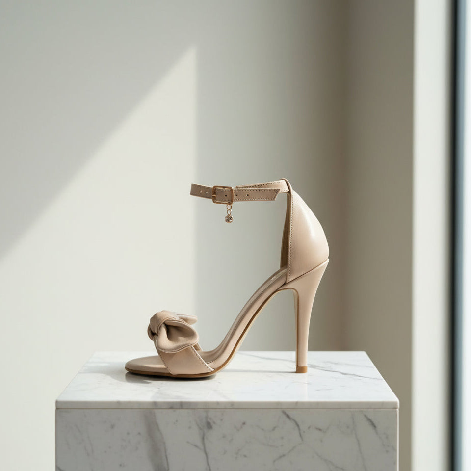 Beige high-heeled sandal on a marble surface with a neutral background