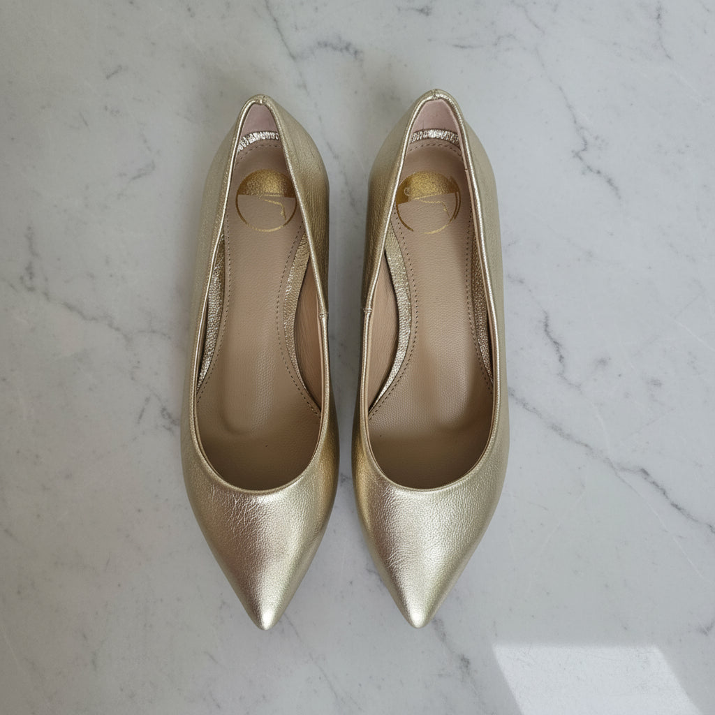 Pair of gold high-heeled shoes on a marble surface