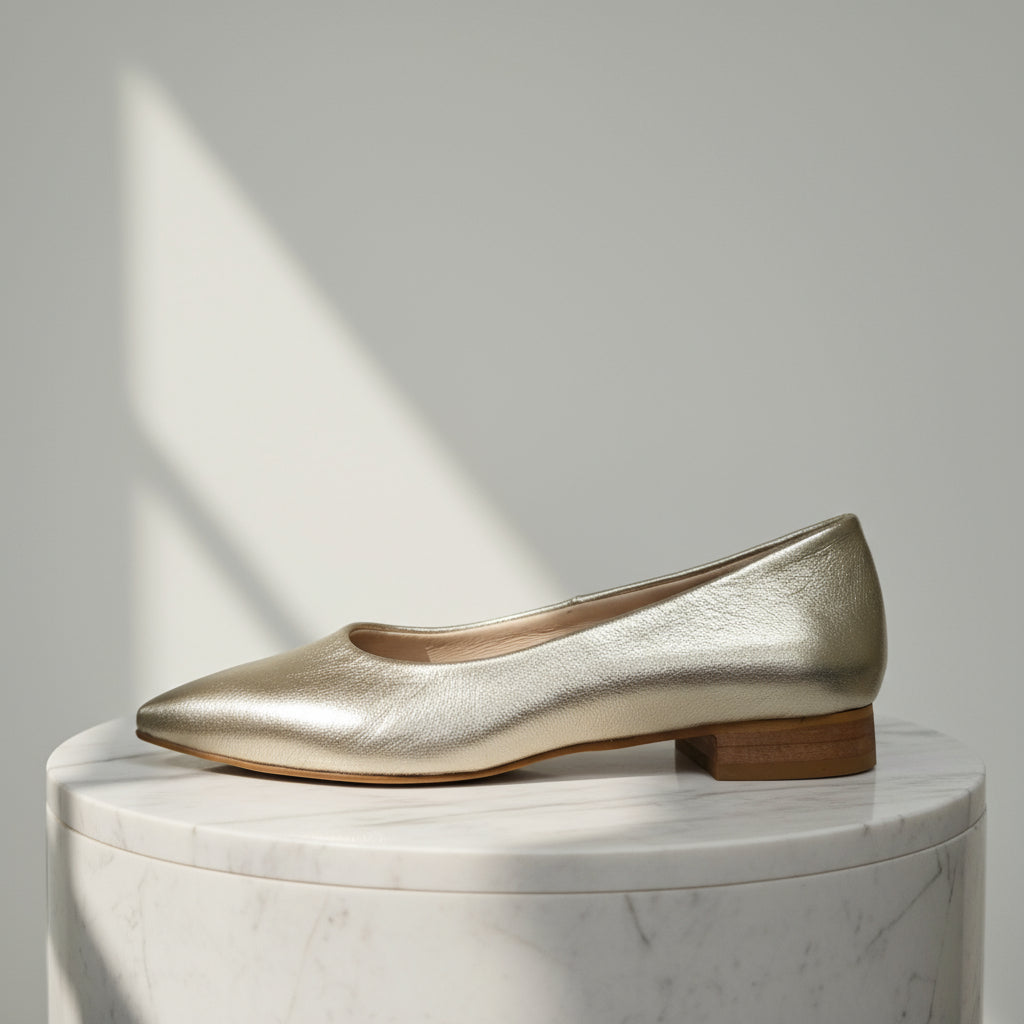 Side profile of petite small size gold leather ballerinas showing wooden low heel.