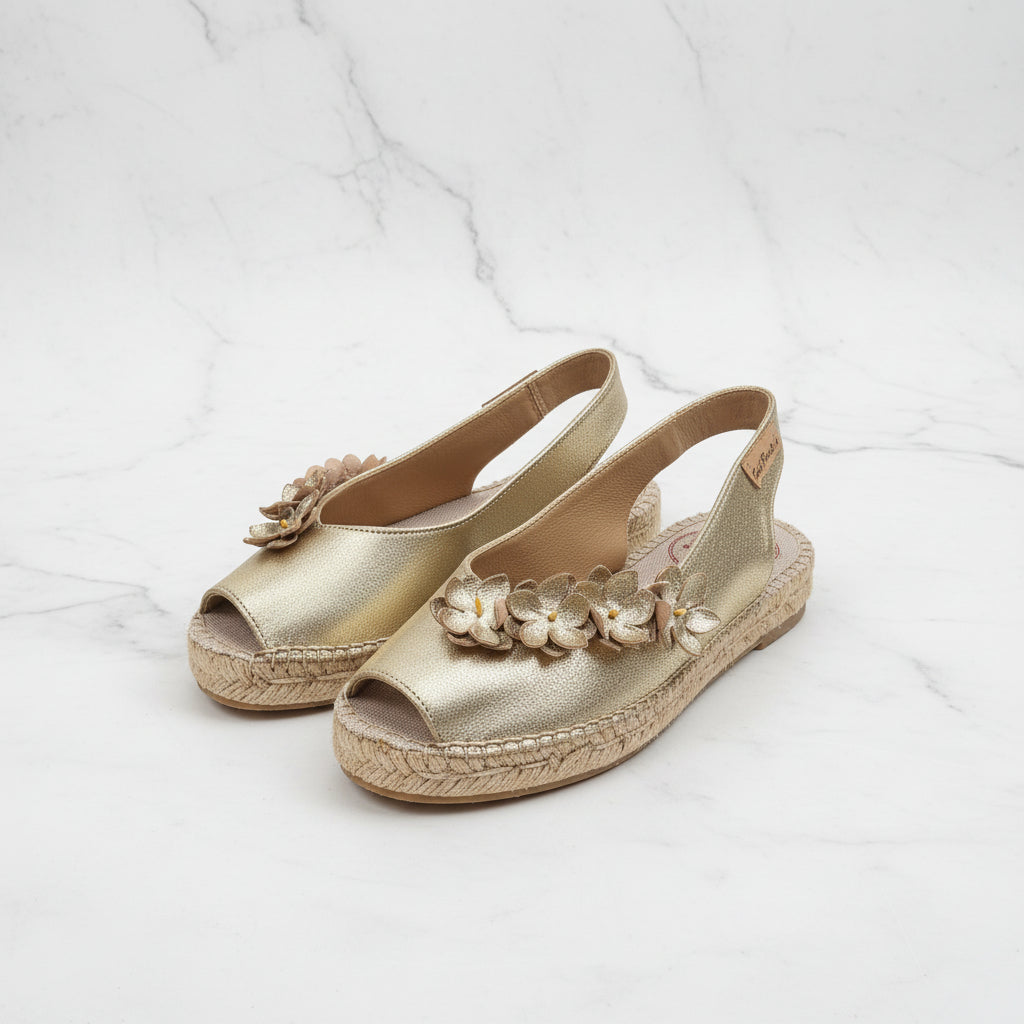 Gold sandals with floral decorations on a white background