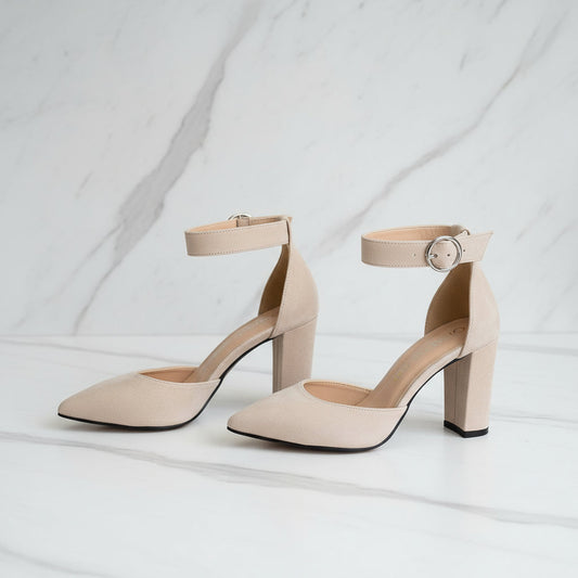 Pair of beige high-heeled shoes with ankle straps on a white background