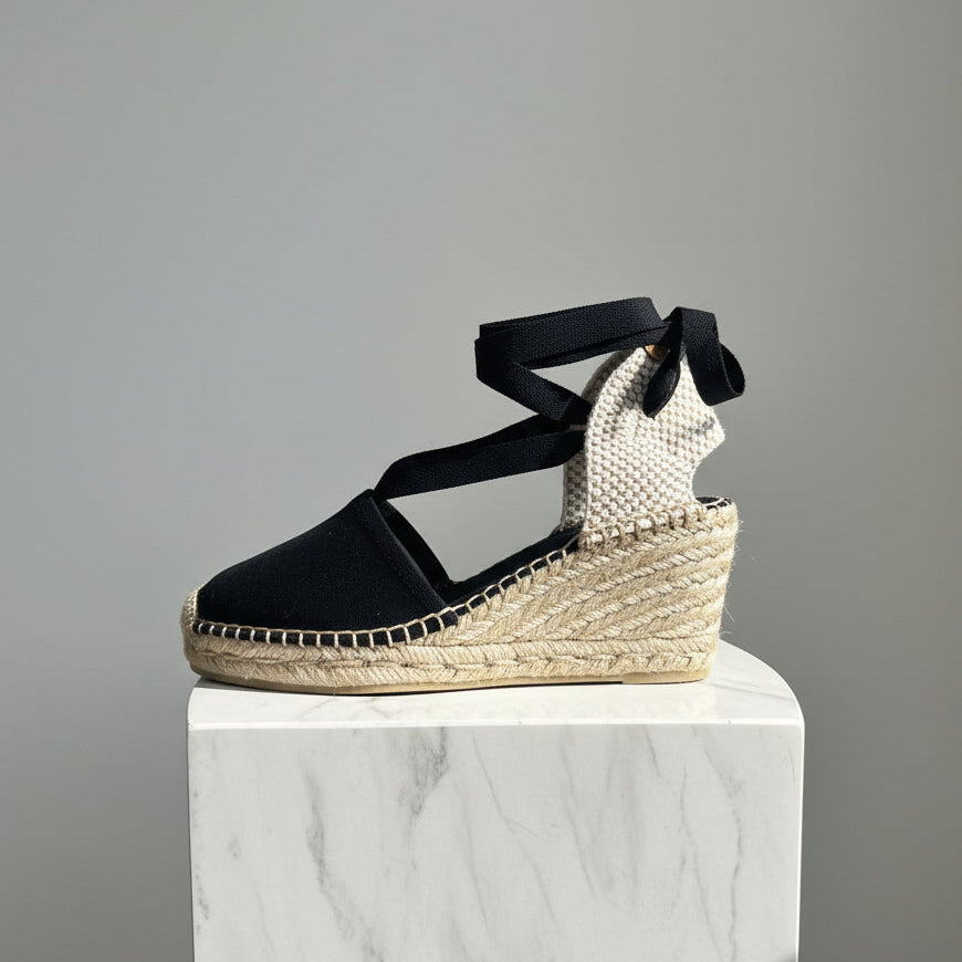 Black wedge sandal with espadrille sole on a gray background