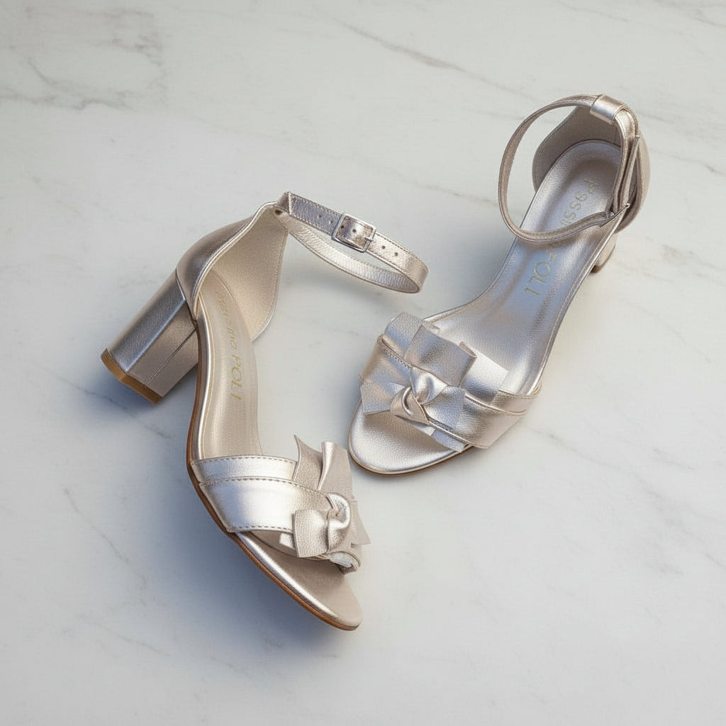 Pair of gold high-heeled shoes on a light marble background