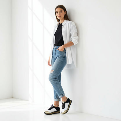 Pair of black and white sneakers with gold accents on a marble surface