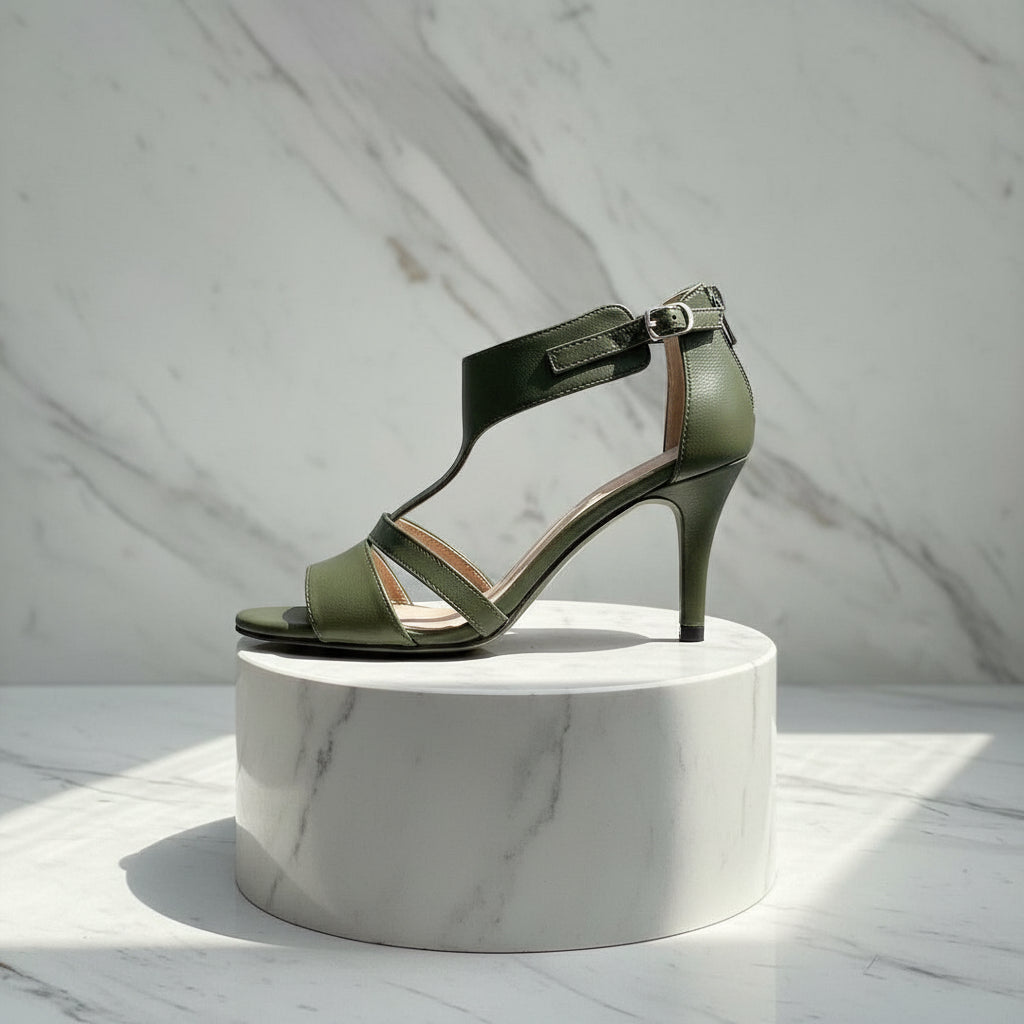 Green sandal on a white marble pedestal against a light gray marble background