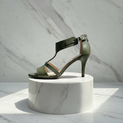Green sandal on a white marble pedestal against a light gray marble background