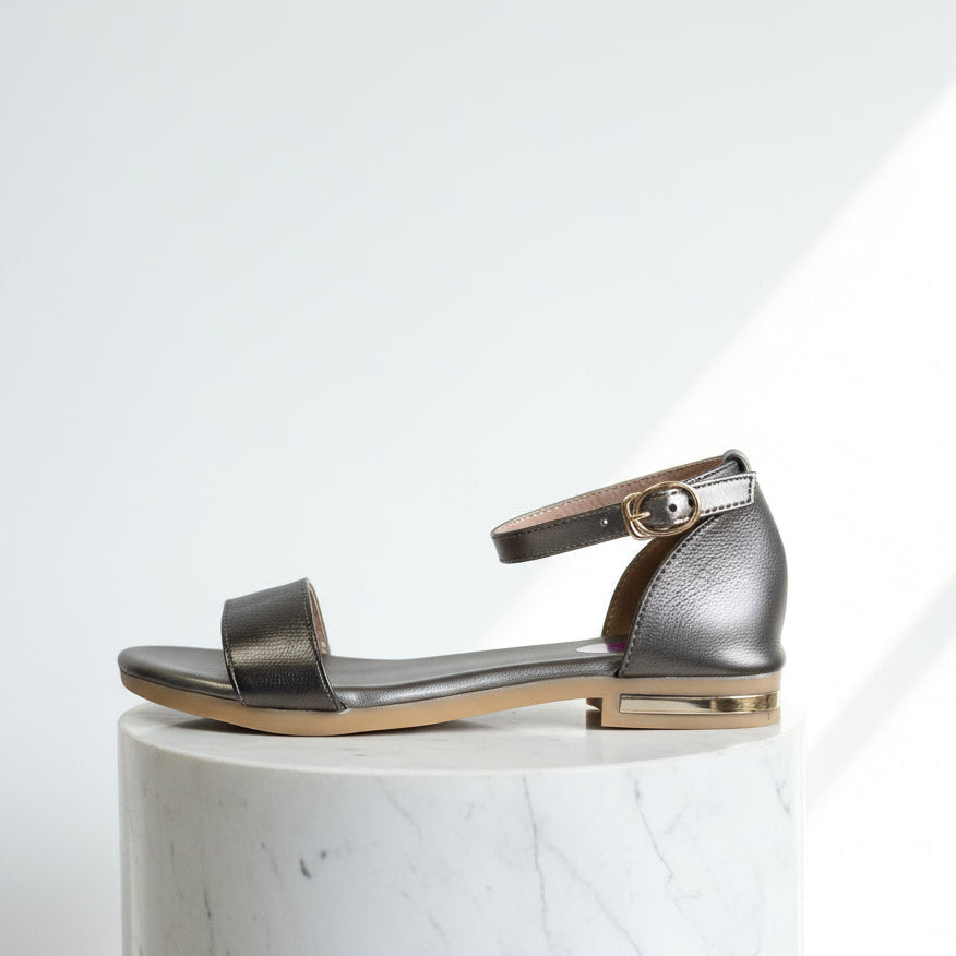 Silver sandal on a white marble pedestal with a white background