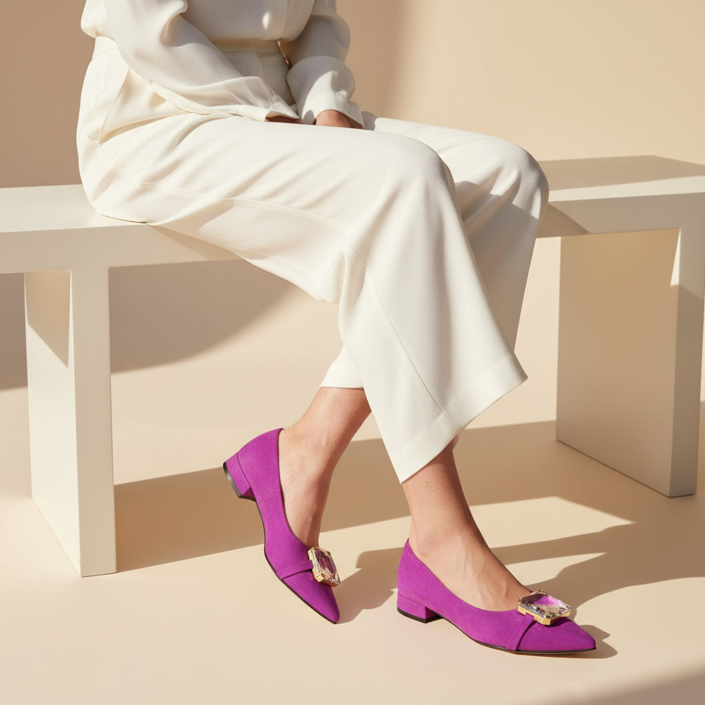 Person wearing white outfit and purple shoes with gold accents sitting on a bench.