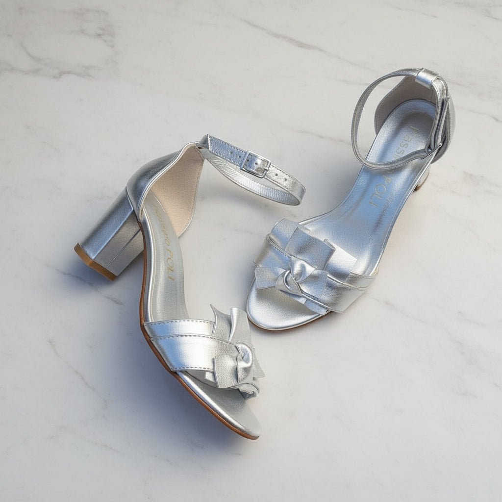 Silver high-heeled sandals on a light gray background
