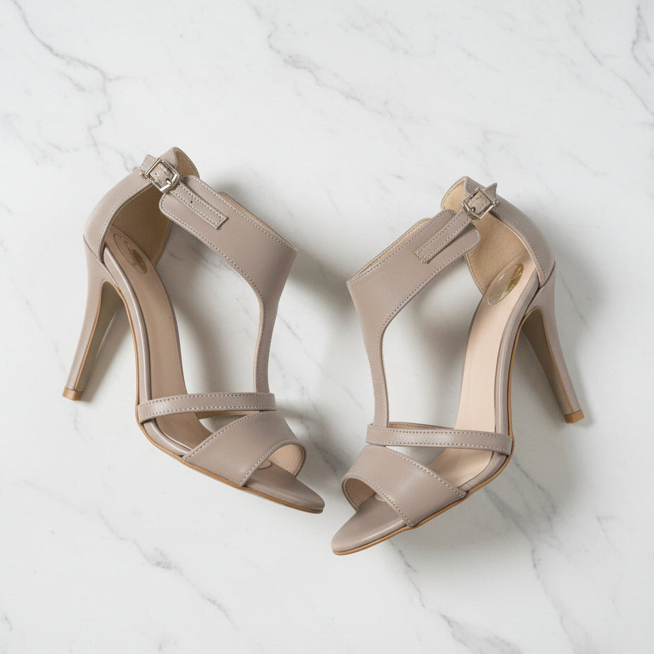 Pair of beige high-heeled sandals on a marble surface
