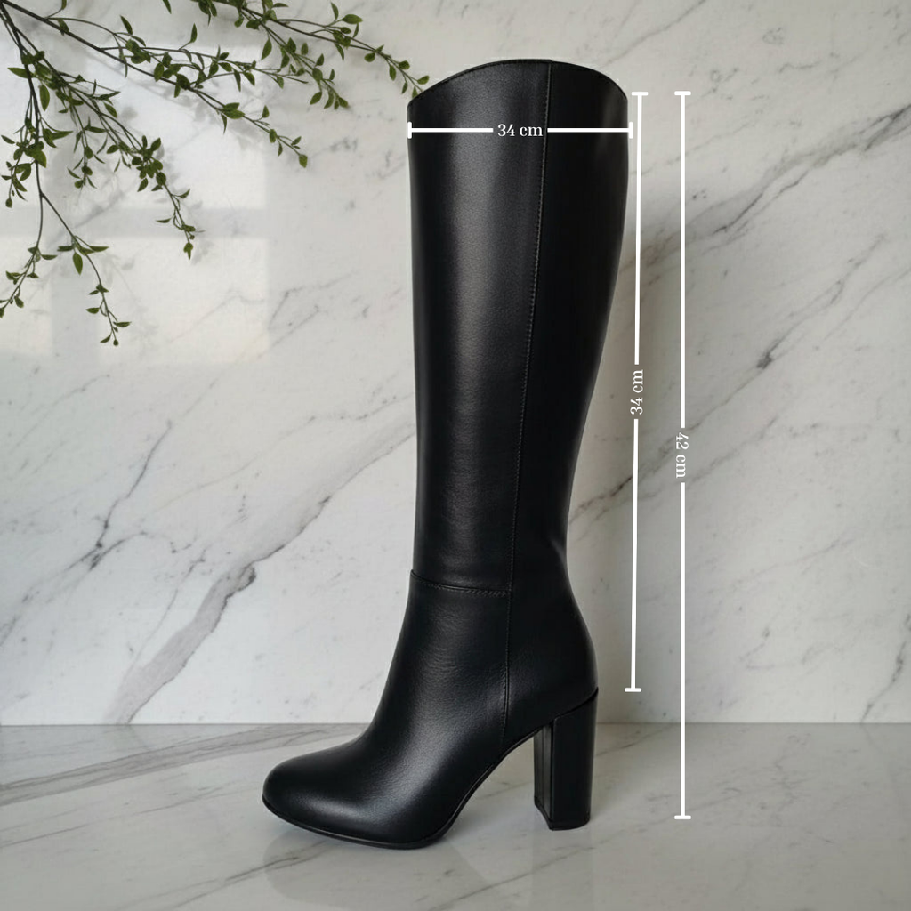 Black leather knee boots set on a block heel and marble floor.