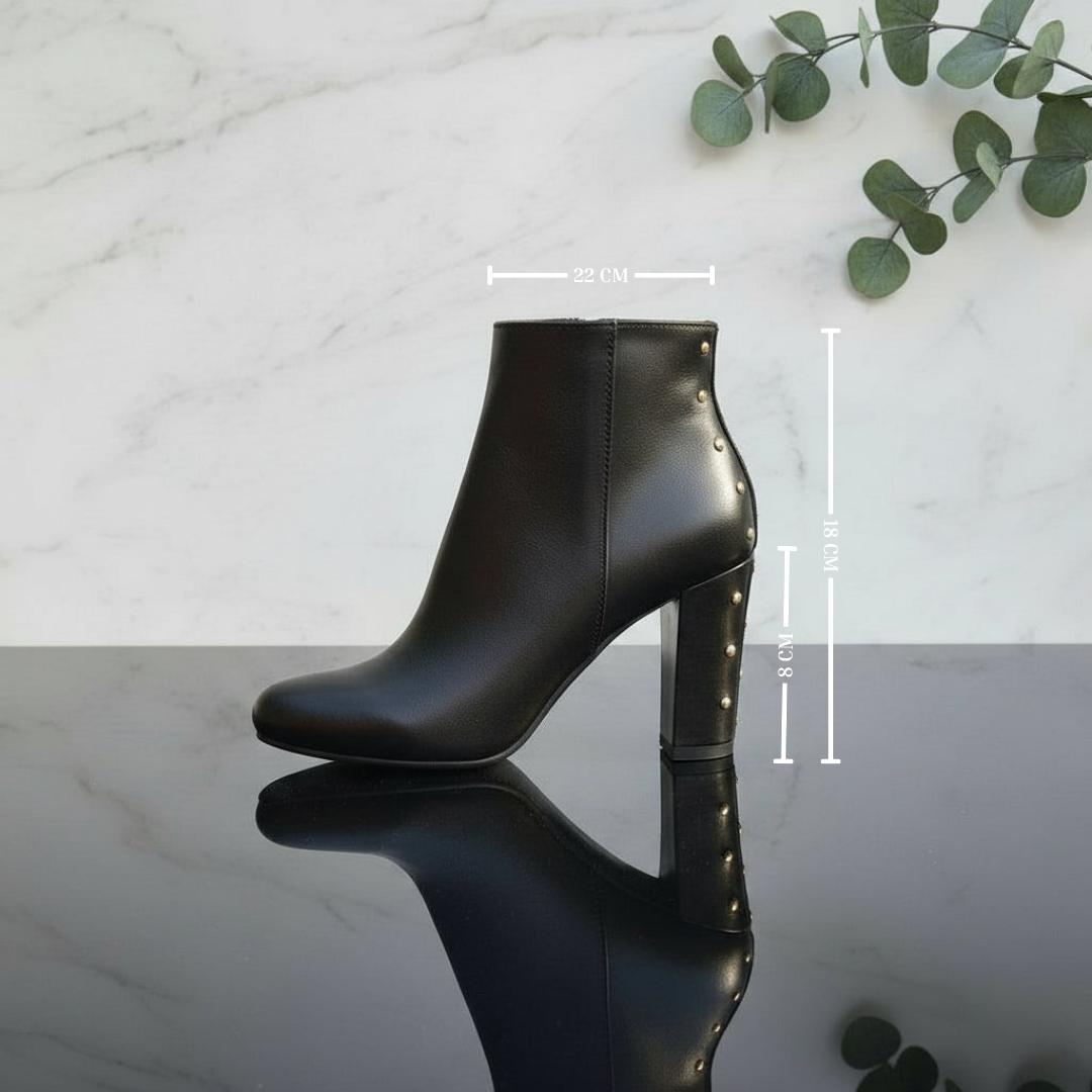 Black ankle boot with measurements on a marble surface