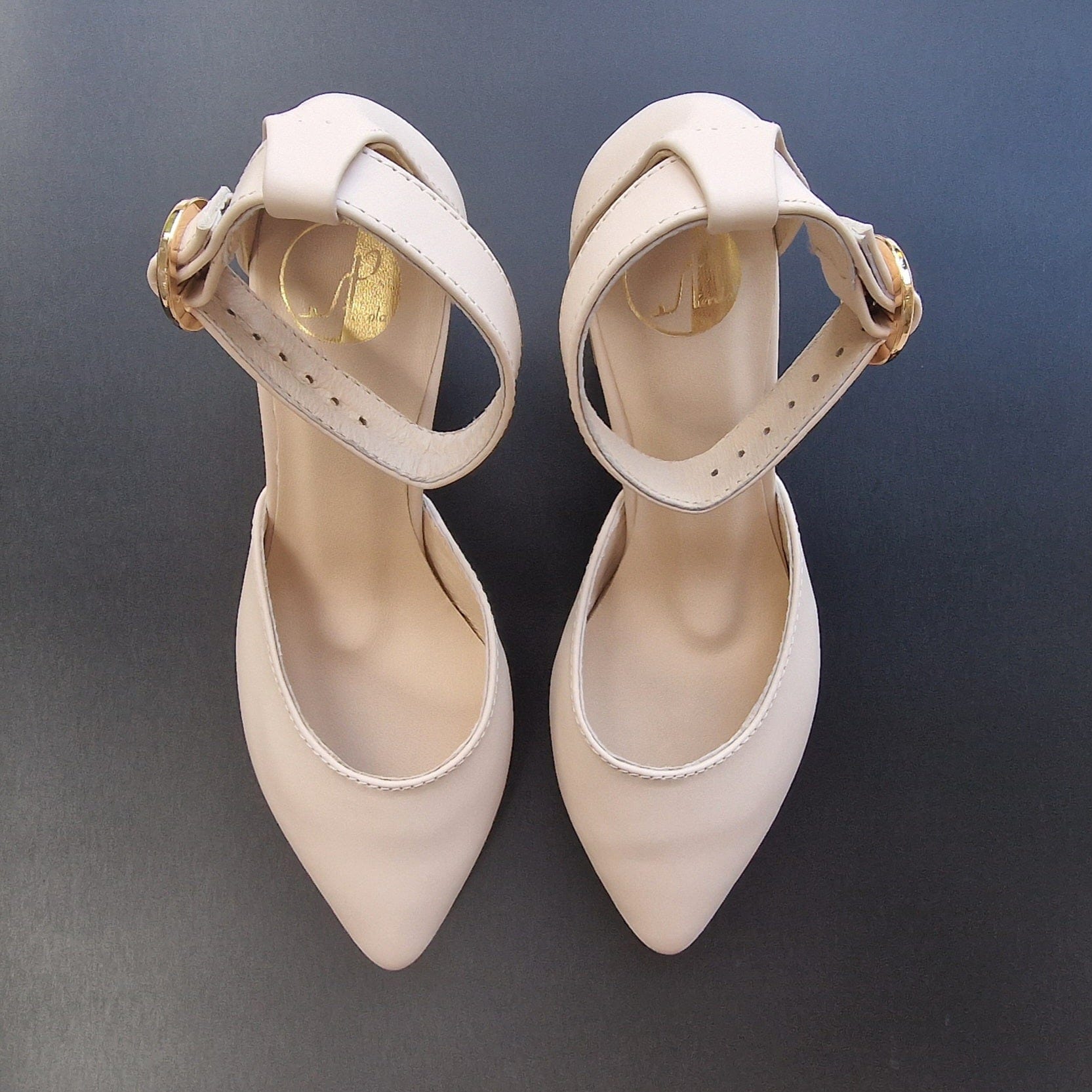 Pointed toe court shoes with an ankle strap in nude leather