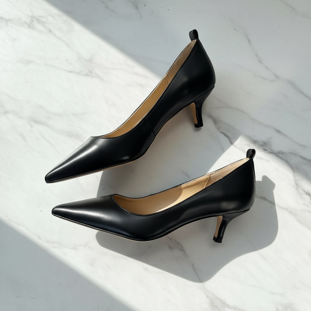 Pair of black high-heeled shoes on a light marble surface