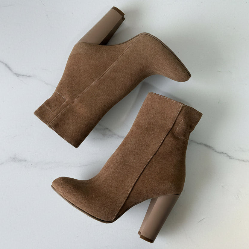 Pair of brown suede ankle boots on a light gray background