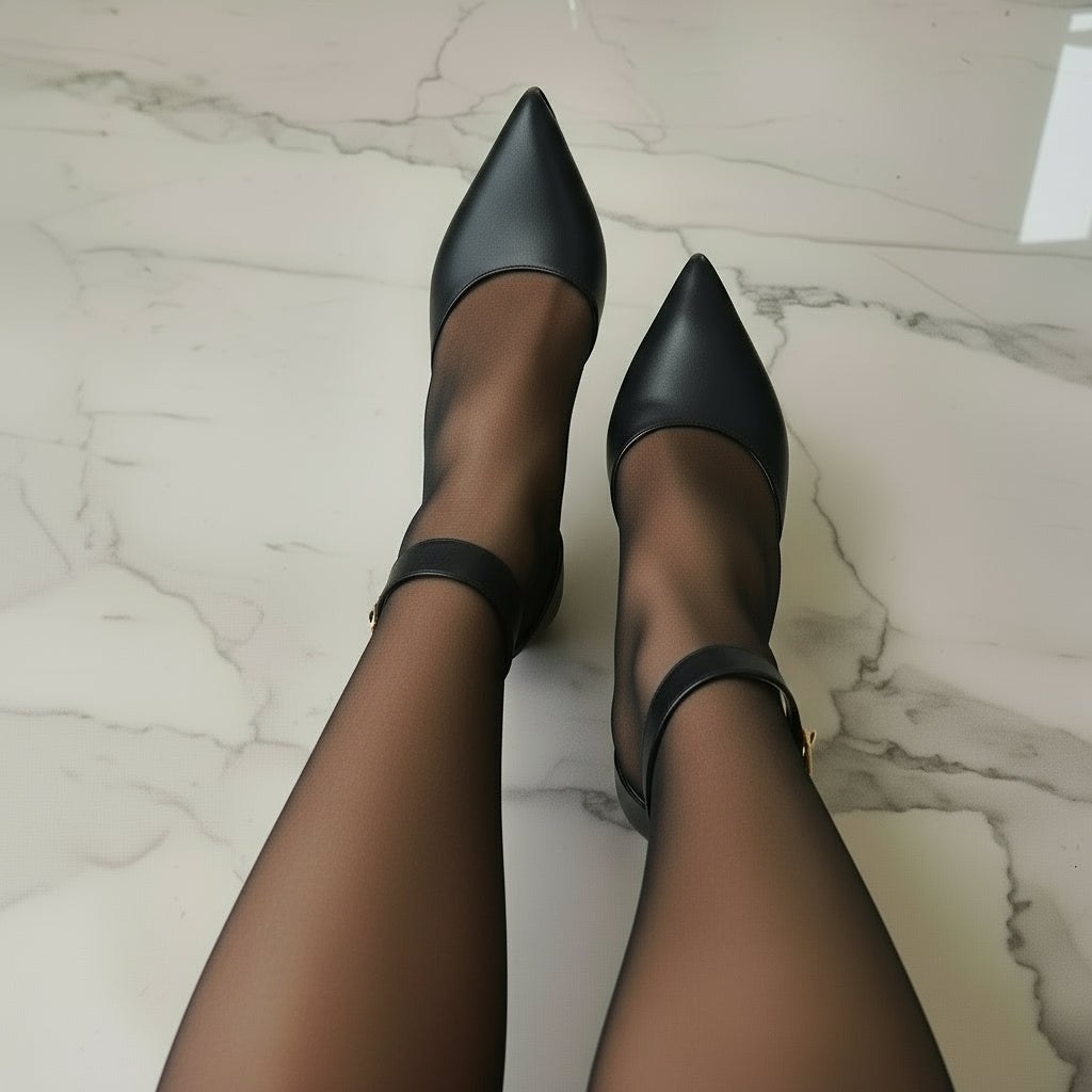 Woman wearing pointed toe ankle strap shoes in black leather