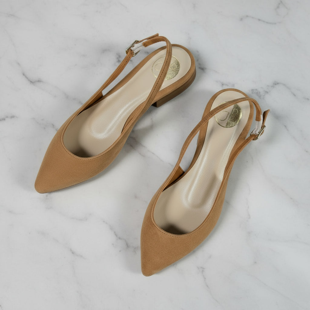 Top view of petite tan suede slingback pointed toe women’s shoes on marble surface with green plant.