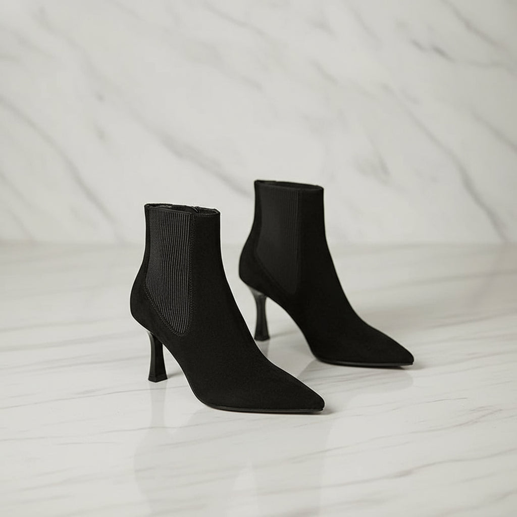 Pair of black high-heeled ankle boots on a light gray background