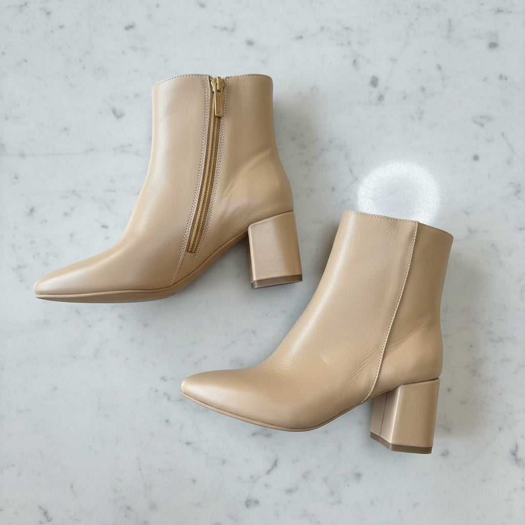 Pair of beige ankle boots with block heels on a tea white grey marble floor