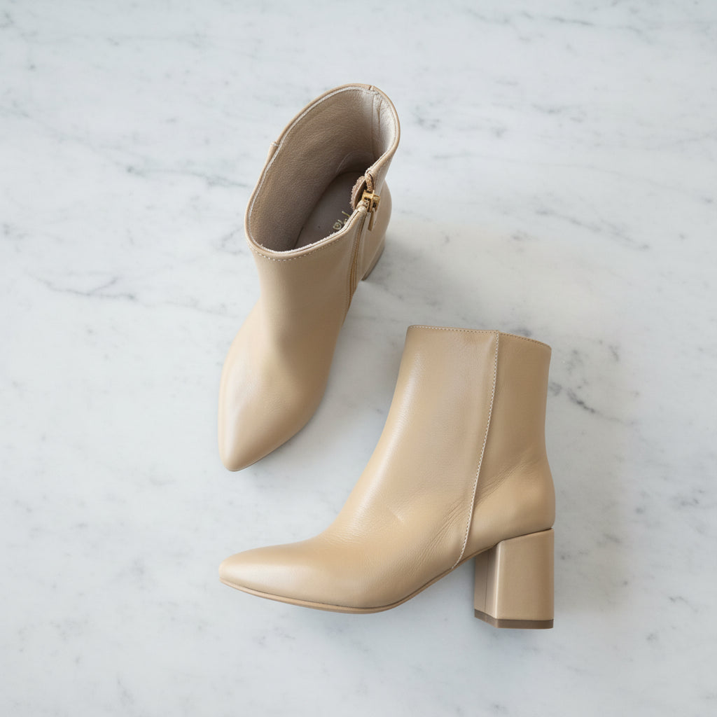 Pair of beige ankle boots on a white marble floor