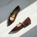 A pair of women's pointed-toe Mary Jane flats in dark burgundy suede with brown trim and straps, displayed on a white surface.