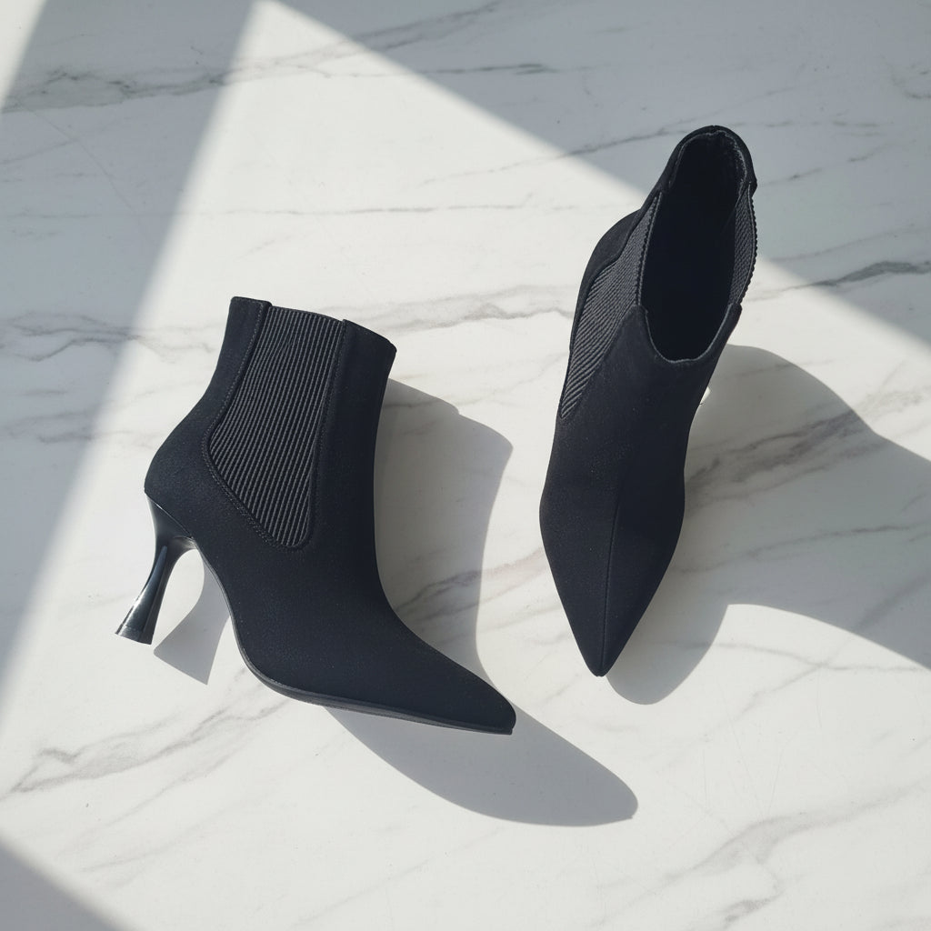 Black high-heeled ankle boots on a light gray floor
