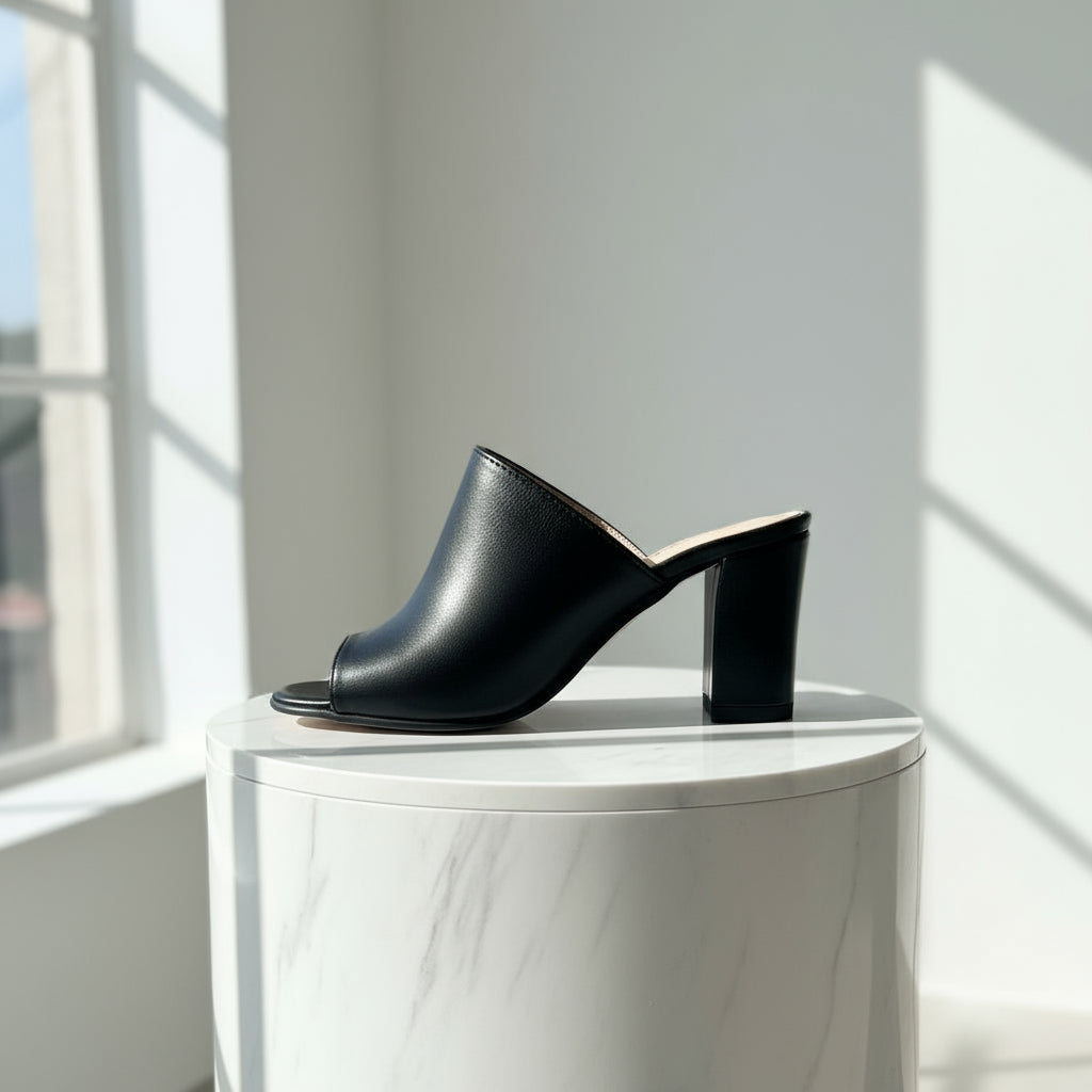 Black leather mules on a marble surface