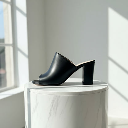 Black leather mules on a marble surface