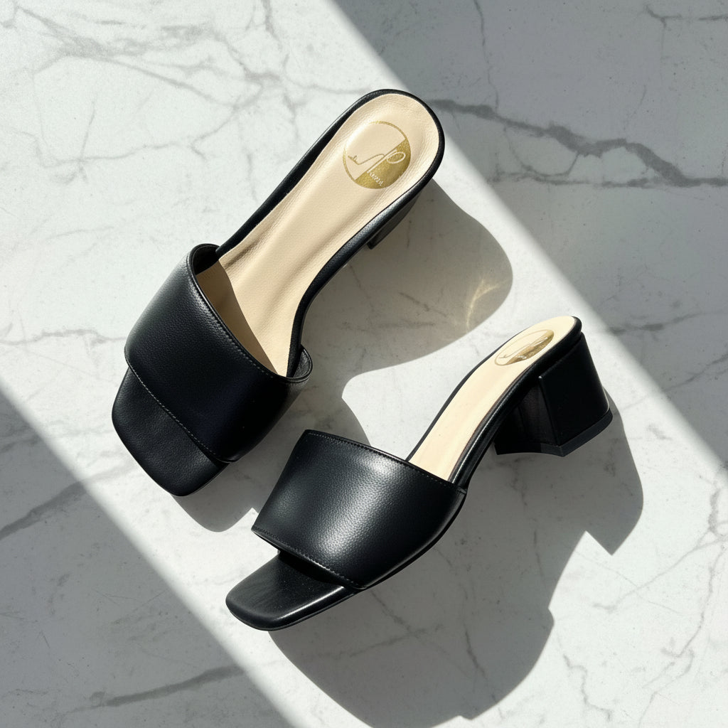 Black open-toe high-heeled shoes on a light gray marble surface