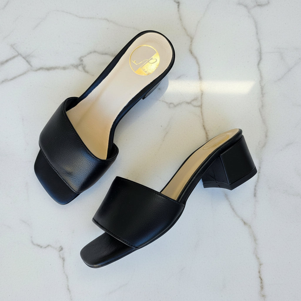 Black high-heeled shoes on a marble surface