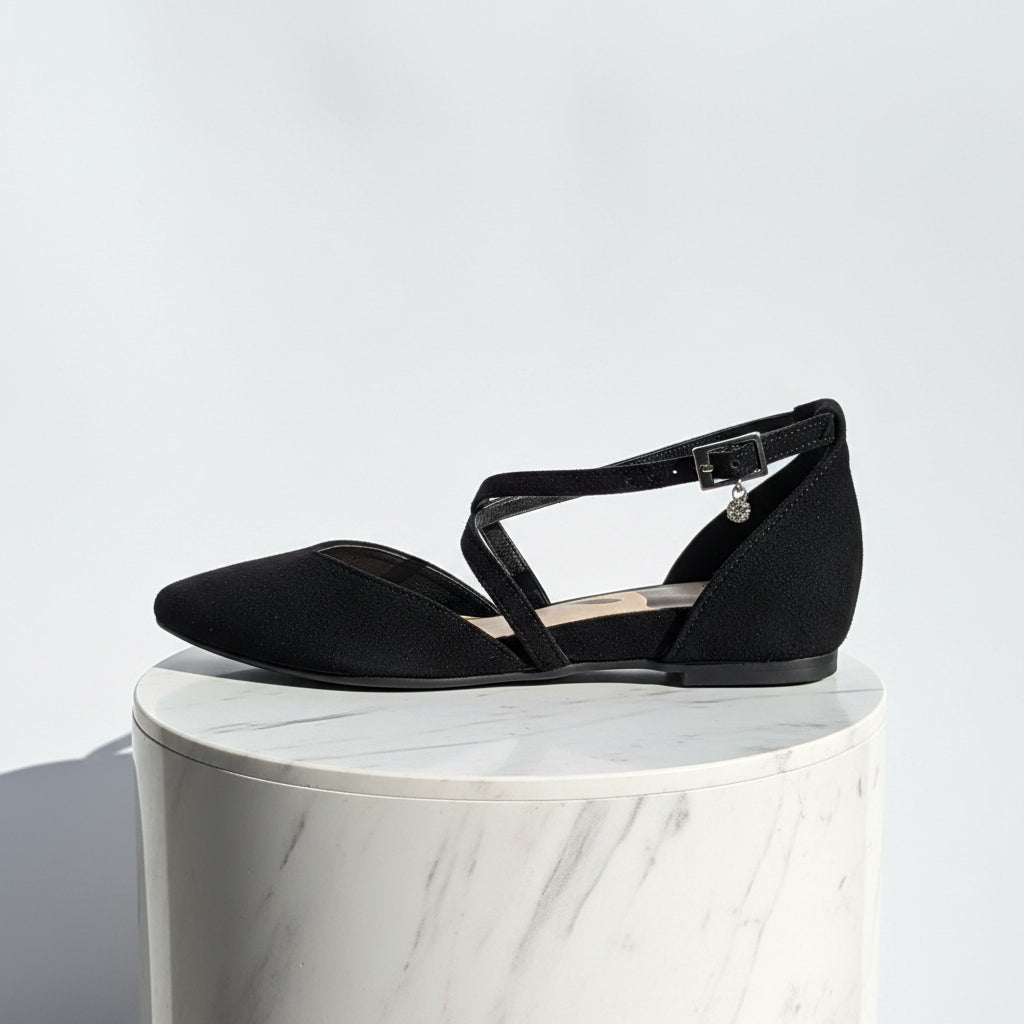 Black flat shoe with ankle strap on a white surface