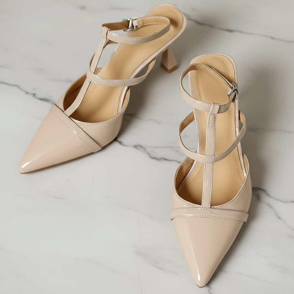 Pair of beige high-heeled shoes with strappy design on a marble surface