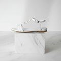 White sandal with clear sole on a white marble block