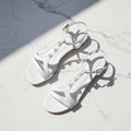 Pair of white sandals with pearl embellishments on a marble surface