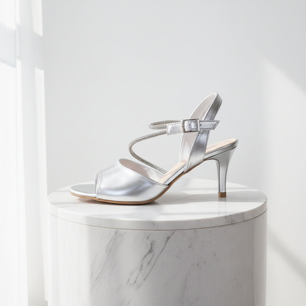 Silver high-heeled sandal on a marble pedestal against a white background