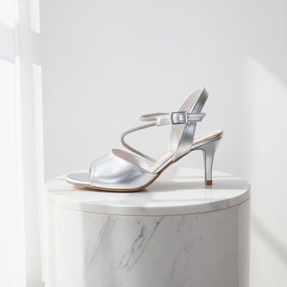 Silver high-heeled sandal on a marble pedestal against a white background