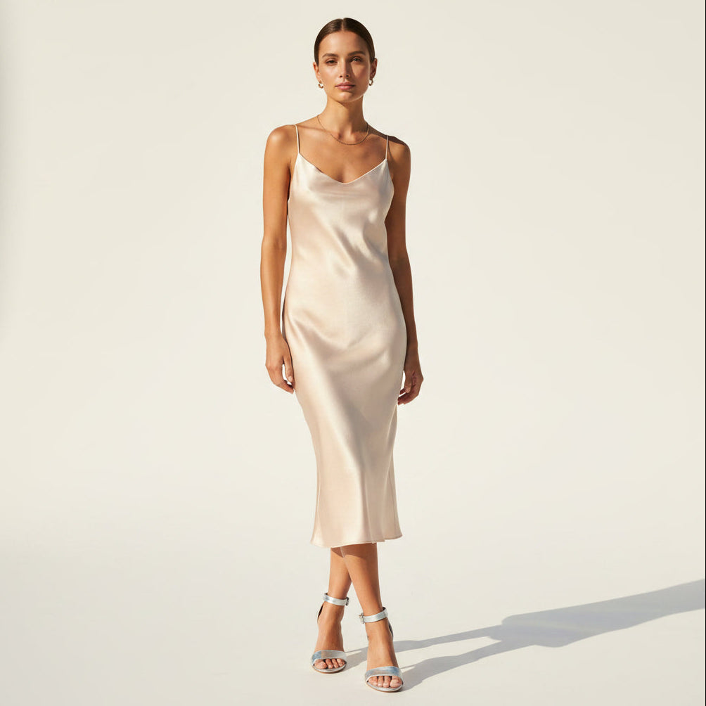 Woman wearing a beige slip dress against a plain background