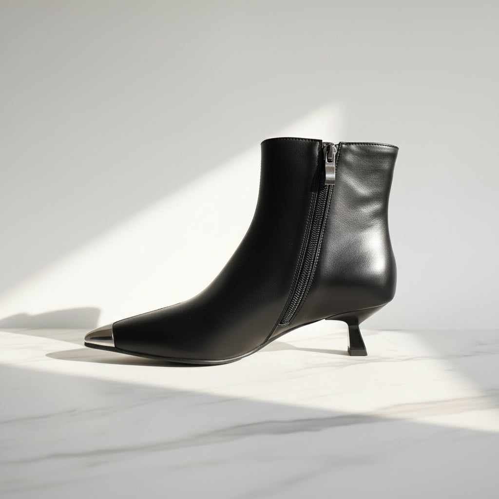 Black leather ankle boots with a kitten heel on a light background