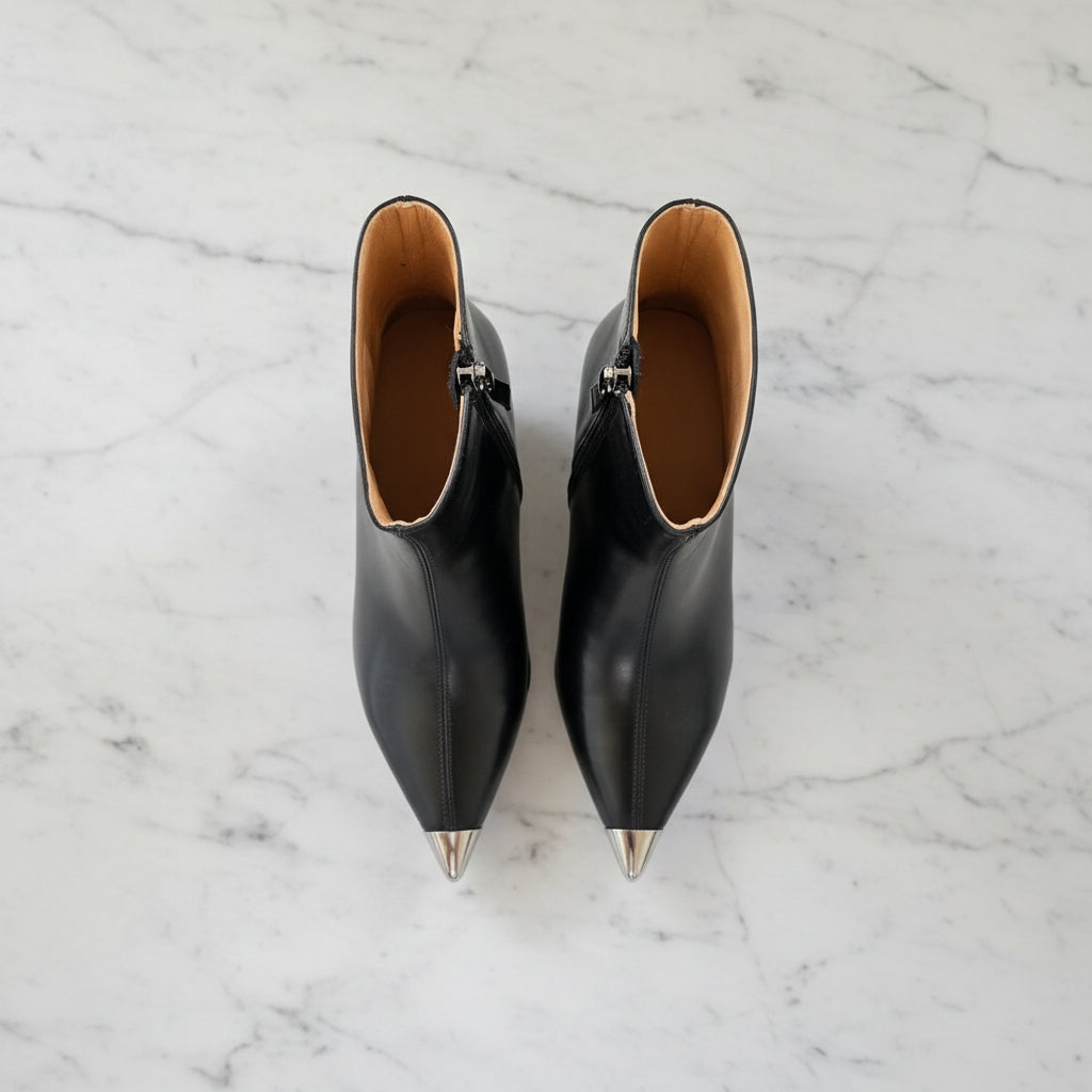 Pair of black pointed-toe boots on a marble surface
