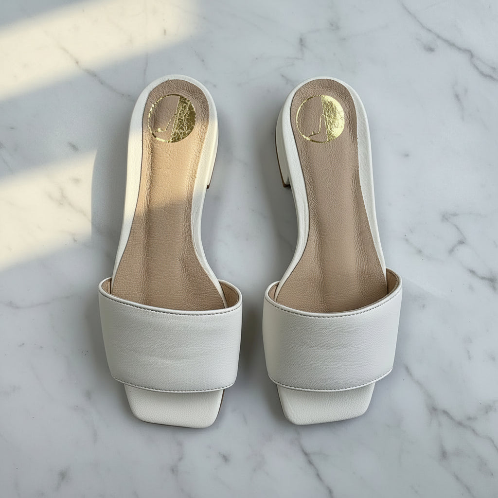 Pair of white high-heeled shoes on a marble surface