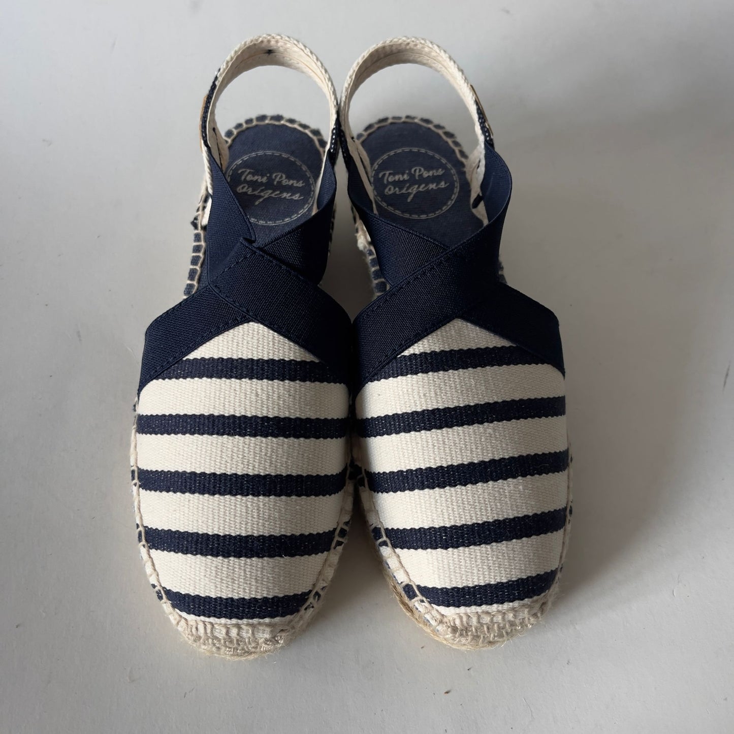 Pair of navy and white striped espadrilles on a light gray background