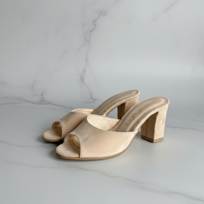 Beige high-heeled sandals on a light gray marble surface