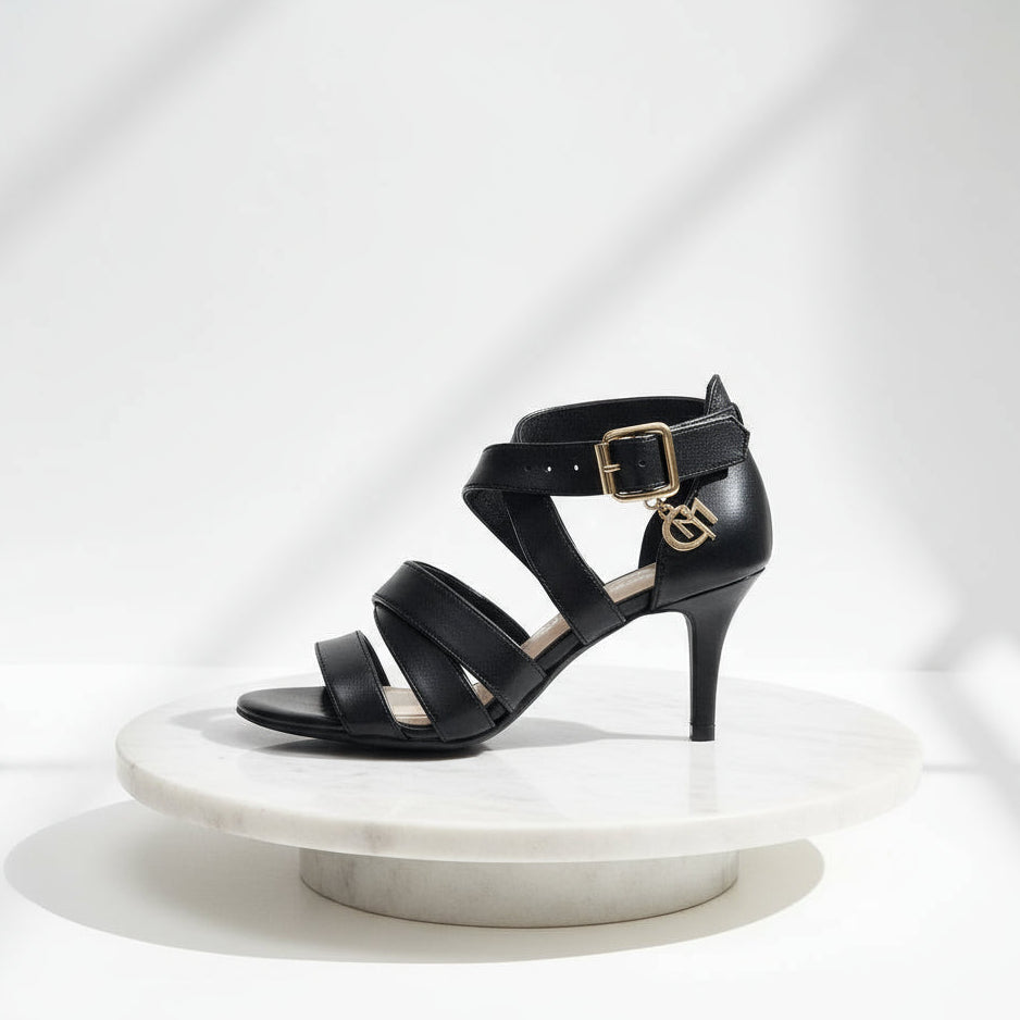 Black strappy high-heeled shoes on a white marble surface