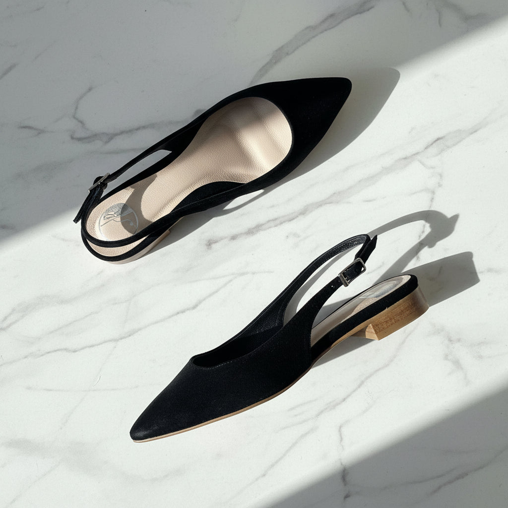 Black pointed-toe slingback heels on a marble surface
