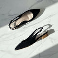 Black pointed-toe slingback heels on a marble surface