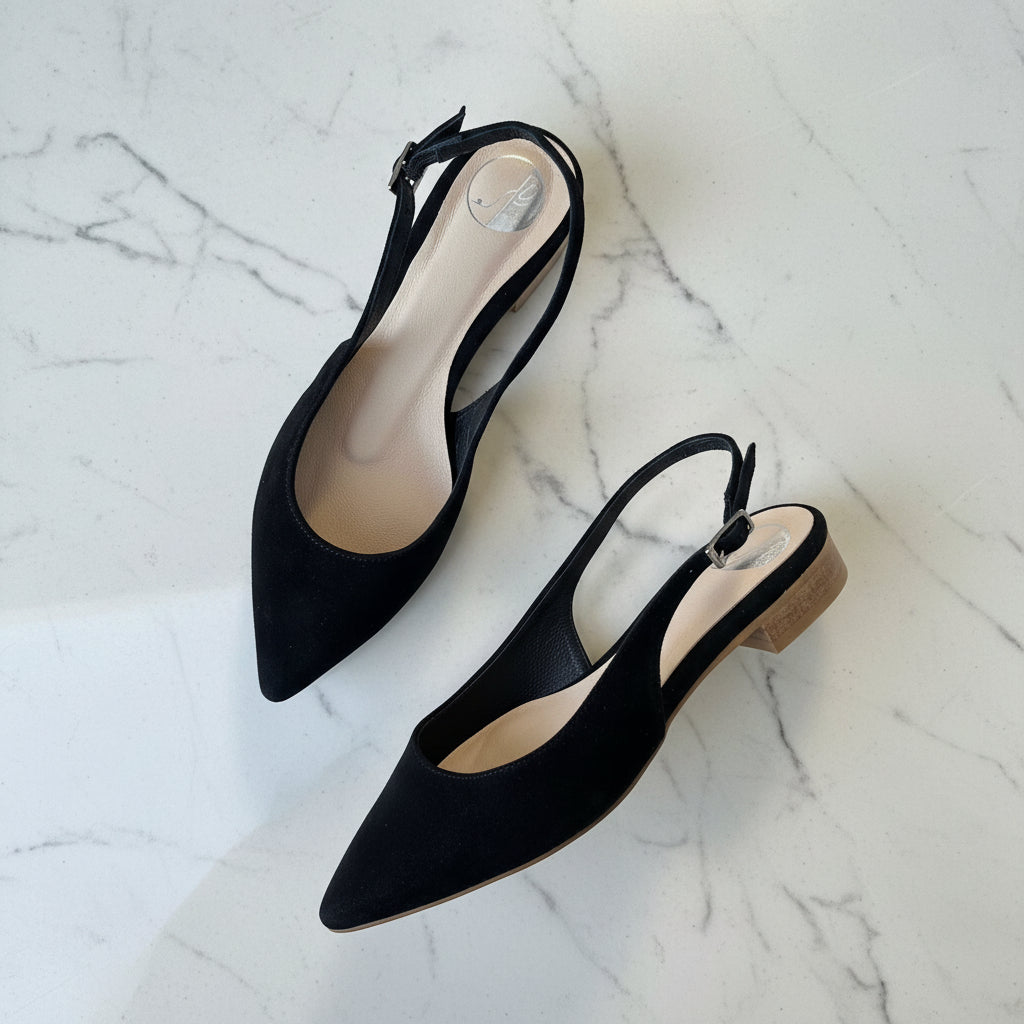 Black pointed-toe slingback heels on a marble surface