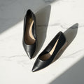Black high-heeled shoes on a marble surface
