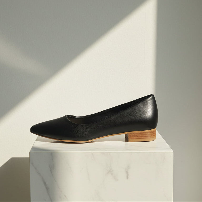 Black leather shoe on a white marble block with a soft shadow