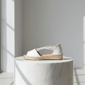 Open toe white strappy espadrille set on a marble stand. 